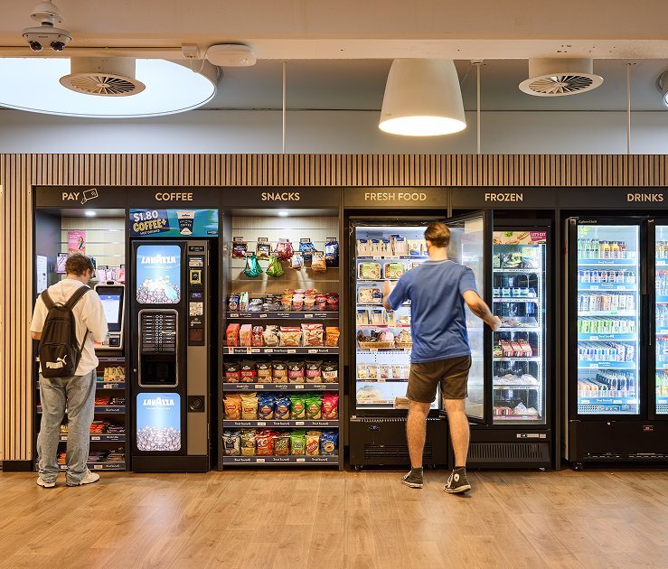 Two people using a micro market vending machine service